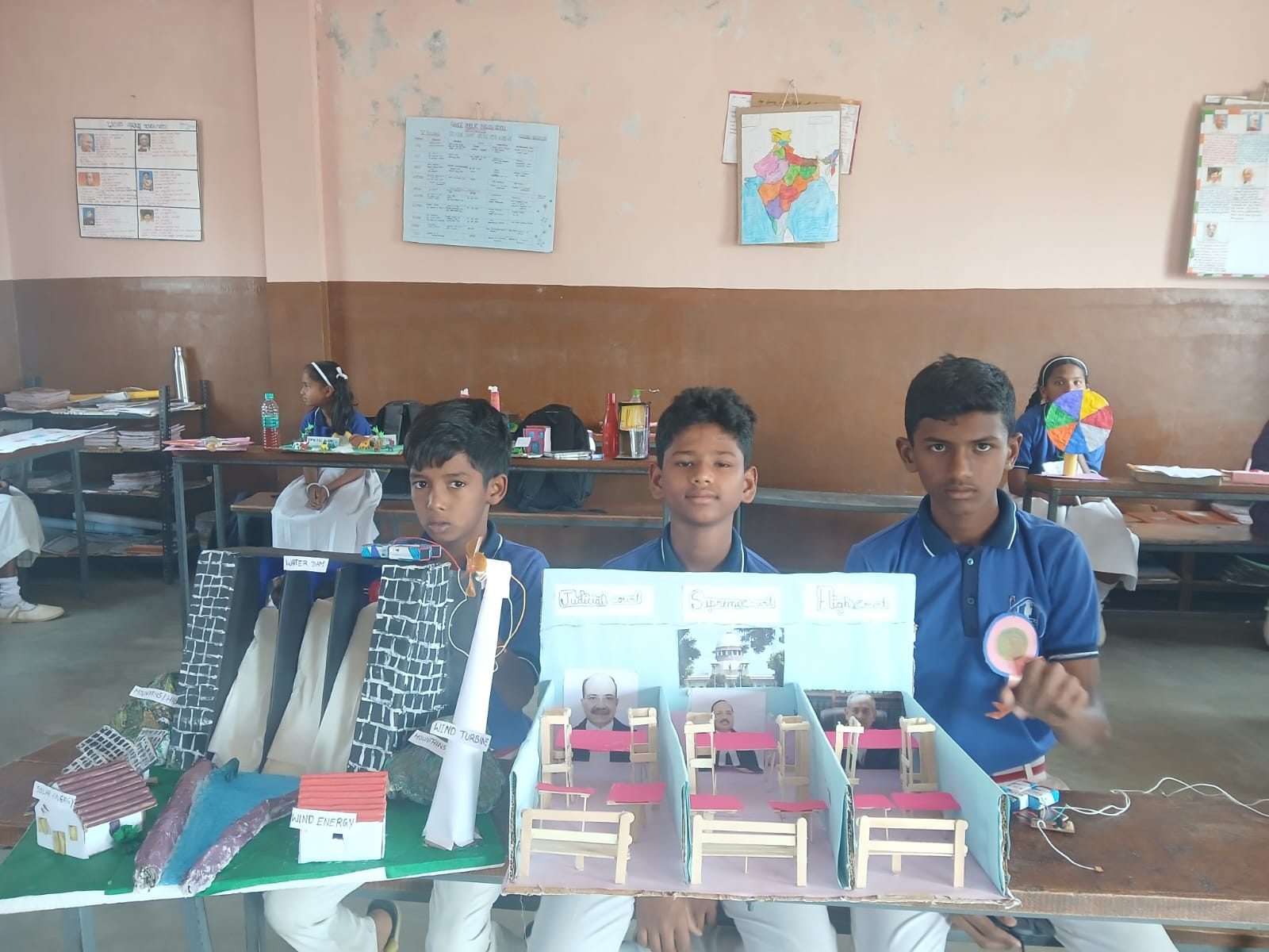 Students stand beside their handmade village and environmental conservation models